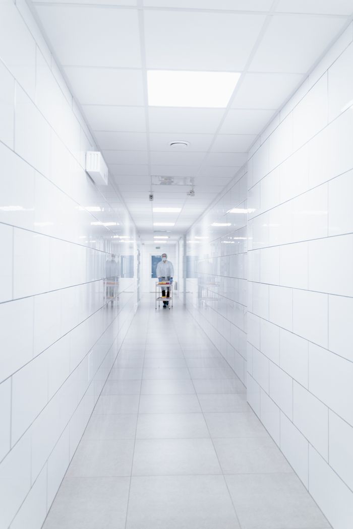 Clean and sterile hospital hallway with a single medical professional in view.