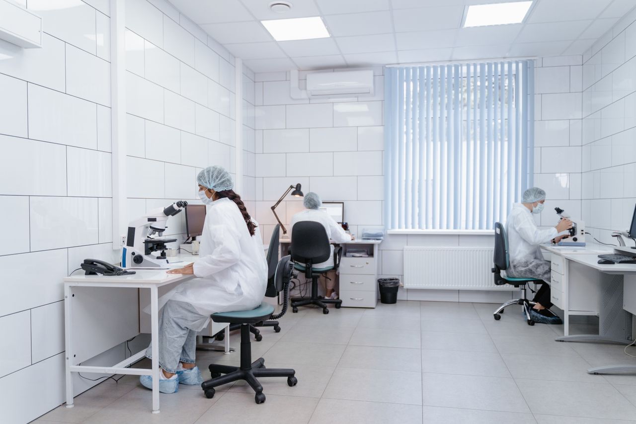 Researchers in a sterile lab conducting scientific experiments using microscopes.